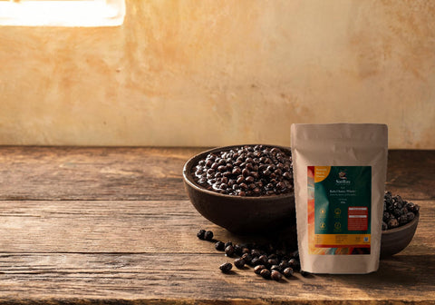 SatRas Desi Kala Chana pouch beside a clay bowl of soaked black chana and a bowl of dry wrinkled chana on a wooden table