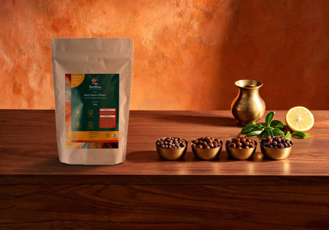 SatRas Haryana desi black chana pouch on a walnut table beside four brass katoris of raw, soaked, boiled and roasted kala chana