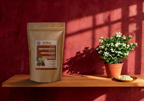 SatRas plant growth promoter pouch beside a mogra jasmine plant in flower and a brass plate of picked buds