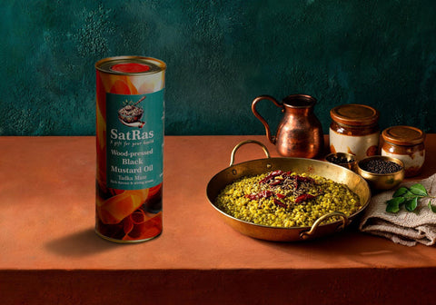 SatRas wood-pressed black mustard oil tin beside a brass kadai of whole green moong dal with a cumin and red chilli tadka